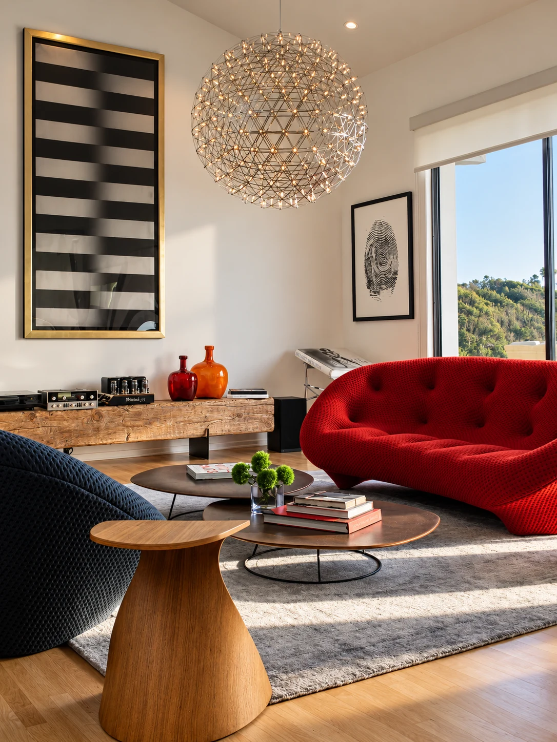 Living room with a curved red sofa, contemporary art, and a sculptural chandelier